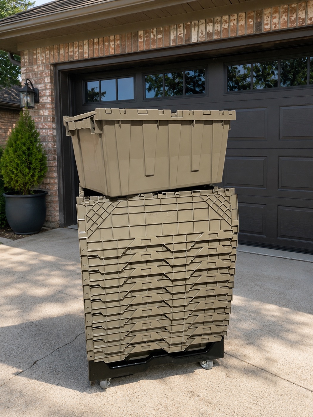 A stack of reusable moving totes on a dolly in a suburban driveway